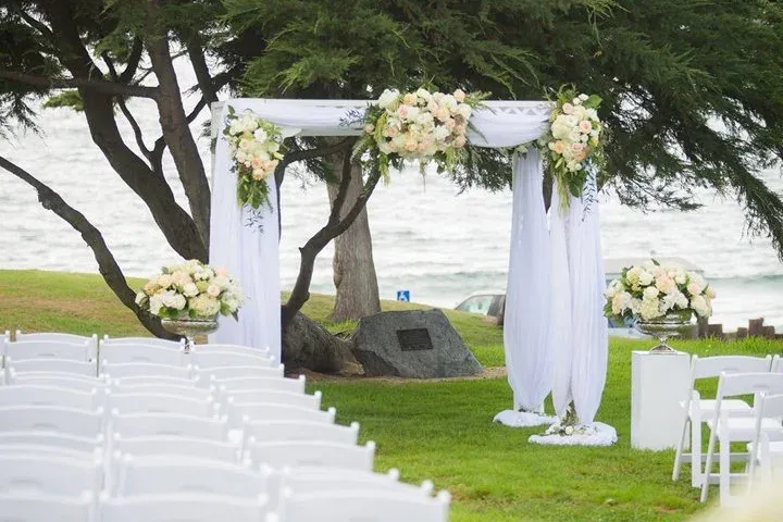 Beachfront wedding ceremony setup with a floral arch and ocean views at Redondo Beach Historic Library